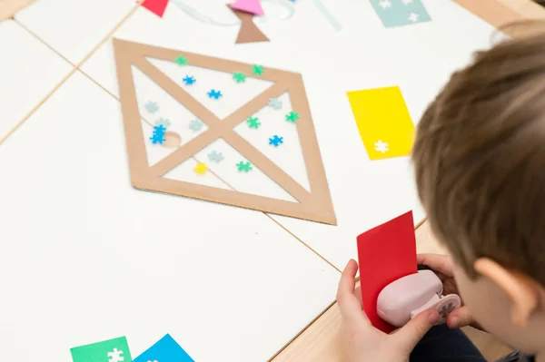 The child is creating a kite. The detail of the puzzle is a symbol of autism. Easy 5 minute crafts. Early preschool education for young children. Zero waste. DIY games at home.