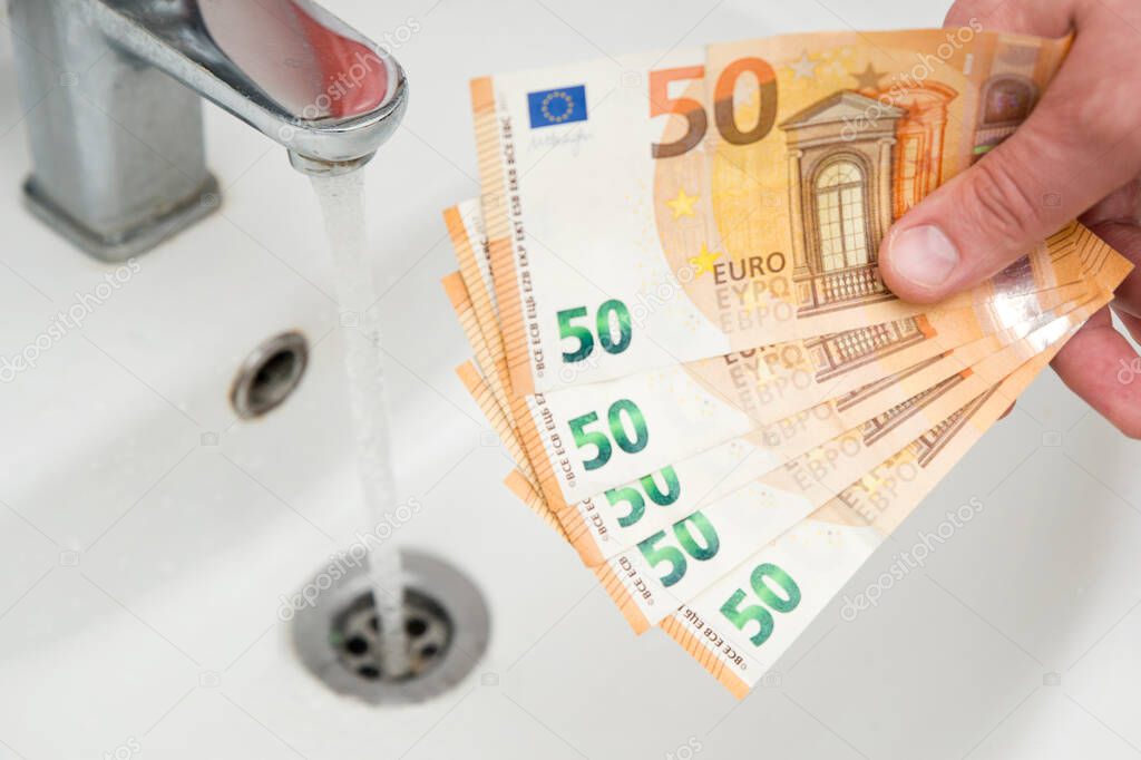 Close up chrome bathroom sink with euro currency banknotes. Concept for increasing water prices and household budget planning. Increasing consumption, green energy.