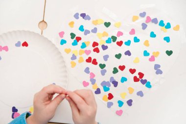 Anneler Günü için kalp. Çocuk yapışkan banta renkli kağıt kalpler yapıştırıyor. Şenlik dekorasyonu. Kadınlar, Düğün, Mutlu Sevgililer Günü konsepti, 14 Şubat.