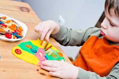 Paskalya konsepti. Çocuk renkli erişteleri yumurta şeklindeki plastiğin üzerine yerleştiriyor. Çocuklar ev fikirleri için oyuncak, çocuk istihdam, iyi motor beceriler, ergoterapi, duyusal terapi