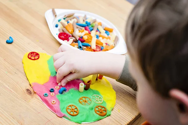 부활절 아이들은 모양의 플라스틱에 색깔있는 국수를 놓습니다 어린이들의 가정용 장난감 — 스톡 사진