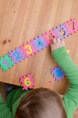 İki yaşındaki bir çocuk köpüklü bulmaca öğrenme numaralarıyla oynuyor. Öğrencileri saymak sayısal zemin oyunu oyuncakları öğrenme oyuncakları