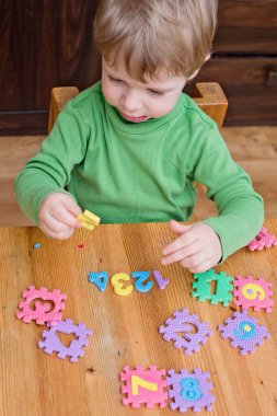 İki yaşındaki bir çocuk köpüklü bulmaca öğrenme numaralarıyla oynuyor. Öğrencileri saymak sayısal zemin oyunu oyuncakları öğrenme oyuncakları