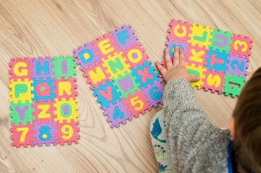 İki yaşındaki bir çocuk köpüklü bulmaca öğrenme numaralarıyla oynuyor. Öğrencileri saymak sayısal zemin oyunu oyuncakları öğrenme oyuncakları