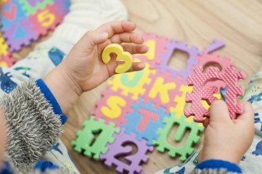 İki yaşındaki bir çocuk köpüklü bulmaca öğrenme numaralarıyla oynuyor. Öğrencileri saymak sayısal zemin oyunu oyuncakları öğrenme oyuncakları