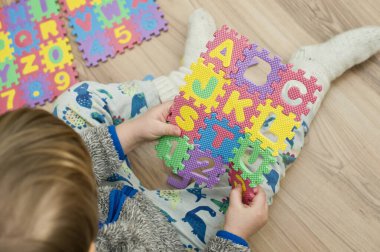 İki yaşındaki bir çocuk köpüklü bulmaca öğrenme numaralarıyla oynuyor. Öğrencileri saymak sayısal zemin oyunu oyuncakları öğrenme oyuncakları