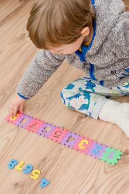 İki yaşındaki bir çocuk köpüklü bulmaca öğrenme numaralarıyla oynuyor. Öğrencileri saymak sayısal zemin oyunu oyuncakları öğrenme oyuncakları