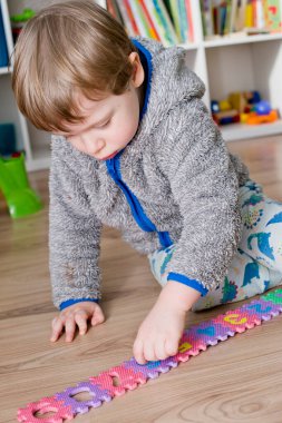 İki yaşındaki bir çocuk köpüklü bulmaca öğrenme numaralarıyla oynuyor. Öğrencileri saymak sayısal zemin oyunu oyuncakları öğrenme oyuncakları