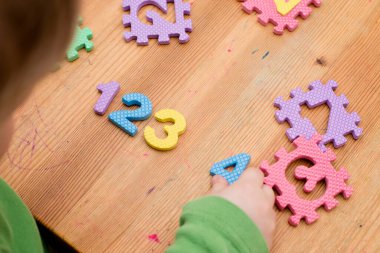İki yaşındaki bir çocuk köpüklü bulmaca öğrenme numaralarıyla oynuyor. Öğrencileri saymak sayısal zemin oyunu oyuncakları öğrenme oyuncakları