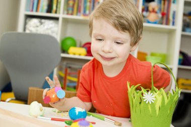 Mutlu Paskalyalar. Paskalya yumurtası boyayan 3 yaşında bir çocuk. Dini bayram. Erken eğitim ve sanatsal anaokulu aktiviteleri.