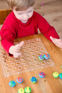 Oyun sayıyorum. Belirtilen numaraya göre doğru sayıda kapak al. Küçük çocuk görevini yerine getirdi. Erken eğitim. Oyuncak hayal gücünü, yaratıcılığı, el-göz koordinasyonunu canlandırır..