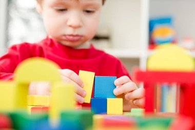 Genç bir inşaatçı. Çocuk ahşap bloklardan şehir inşa ediyor. Çocuk Oyun Odası. Geliştirme ve İnşaat Konsepti. Öğrenme oyuncağı hayal gücünü, yaratıcılığı, el-göz koordinasyonunu canlandırır..