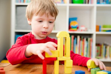 Genç bir inşaatçı. Çocuk ahşap bloklardan şehir inşa ediyor. Çocuk Oyun Odası. Geliştirme ve İnşaat Konsepti. Öğrenme oyuncağı hayal gücünü, yaratıcılığı, el-göz koordinasyonunu canlandırır..