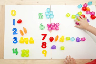 Sayılar ve oyuncaklar. Yapay meyve ve rakamlar. Çocukların saymayı öğrenmesi için bir fikir. Montessori kavramı, erken eğitim.
