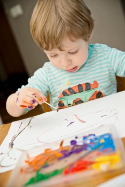 Evde Paskalya aktiviteleri. Karantina sırasında dalga geçin. Çocuk, yumurta şekillerini kulaklık ve guaj ile süslemiş. Evde DIY oyunları.