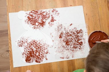 Ev yapımı balonlu film boyama tekniği ve göbeğine ponpon topları yapıştırılmış oyuncak ayı. Küçük çocuk üretim aşamasında..