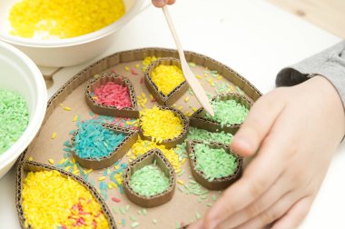 Paskalya yumurtasını renkli pirinçle süslemek. Çocukların oynarken motor becerilerini geliştirmeleri için bir araç. El-göz koordinasyonu için DIY oyuncağı.