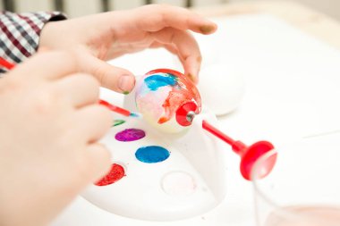 Mutlu Paskalyalar. Paskalya yumurtaları boyayan çocuk. Dini bayram. Erken eğitim ve sanatsal anaokulu aktiviteleri. Çocuk eğleniyor ve ziyafet çekiyor..