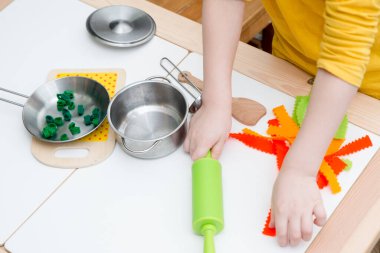 Anne, yemek zamanı! Çocuk oyuncak mutfağında oyuncak yemek hazırlıyor. Çocuk yetişkin sorumluluklarını taklit ediyor. Evdeki etkinlikler. Yaratıcılığı teşvik eden bir oyun. Makarna hissettim..
