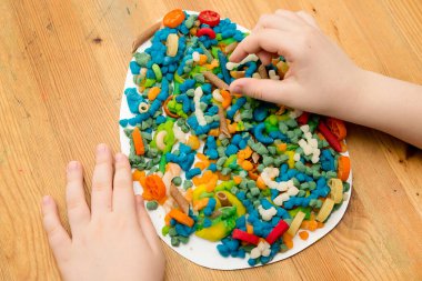 Paskalya konsepti. Çocuk yumurta şeklinde bir kağıda renkli plastik erişte yerleştiriyor. Çocuklar ev fikirleri için oyuncak, çocuk istihdam, iyi motor beceriler, ergoterapi, duyusal terapi