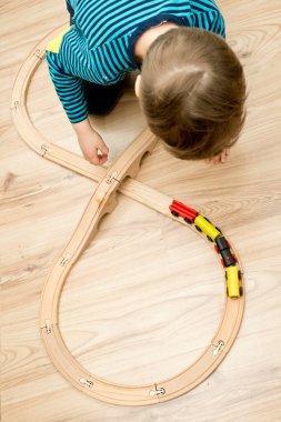 Buharlı trenli ahşap demiryolu. Ahşap zeminde çocuk oyuncağı. Çocuk odası teması. Dikkatsiz çocukluğun, hayallerin, savaşın ve kolay hayatın sembolü..