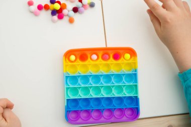 Çocuk duyusal oyuncak Pop-it ile oynuyor. Kaliteli motor becerileri için araç, saymaya başlamak için araç, birincil aritmetik işlemlerini öğrenmek. Parmak uyumu ve rahatlama için bir yatıştırıcı..