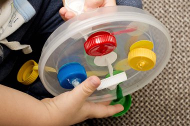 Bir kurdele çek. Bebek için ev yapımı bir oyun. Renkli plastik kapaklar. Rahatlamak ve eğlenmek için terapi görevi. Çocuklar ve engelliler için iyi motor becerileri var..