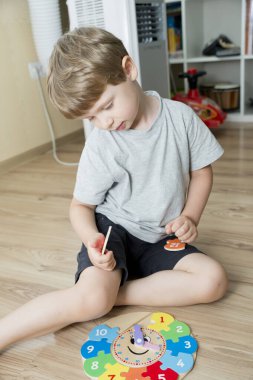 Çocuk, tahta saatle vakit geçirmeyi öğreniyor. Çocuk Eğitimi için Öğrenme Metodu. Anaokulu ya da özel görevler. Montessori yöntembilimi.