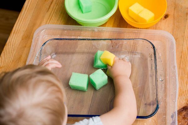 little boy making his first task. brain exercise - select the right color sponges to relevant bowls.