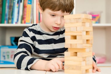 Çocuk bir kule inşa ediyor. Tahta bloklardan yapılmış bir masa oyunu. Stratejini geliştir. Çocuk aktiviteleri. Çocuklar için mantıklı görevler. Konsantrasyon ve dikkat, sabır, Montessori metodu.