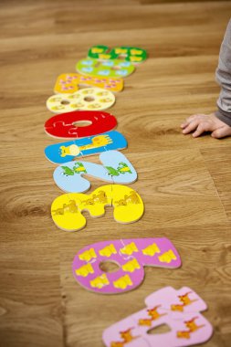 Yeni yürümeye başlayan çocuk yerde oyuncak numaralarıyla oynuyor. Entelektüel matematik oyunu, erken eğitim için anaokulu uygulaması.