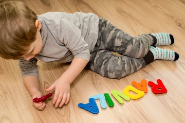 İki yaşındaki bir çocuk keçeli harflerden ismini çeviriyor. Okumayı öğrenmek.