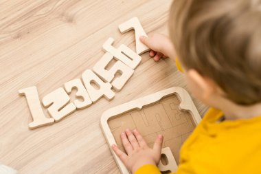 Bulmaca numaraları. Çocuk ahşap numaralarla oynuyor. Erken eğitim, sözlü ve hafıza oyunu.