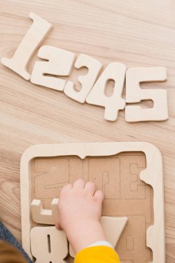 Bulmaca numaraları. Çocuk ahşap numaralarla oynuyor. Erken eğitim, sözlü ve hafıza oyunu.