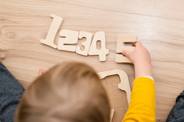 Bulmaca numaraları. Çocuk ahşap numaralarla oynuyor. Erken eğitim, sözlü ve hafıza oyunu.