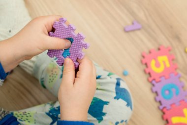 İki yaşındaki bir çocuk köpüklü bulmaca öğrenme numaralarıyla oynuyor. Öğrencileri saymak sayısal zemin oyunu oyuncakları öğrenme oyuncakları