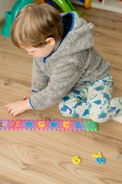 İki yaşındaki bir çocuk köpüklü bulmaca öğrenme numaralarıyla oynuyor. Öğrencileri saymak sayısal zemin oyunu oyuncakları öğrenme oyuncakları