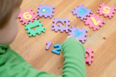 İki yaşındaki bir çocuk köpüklü bulmaca öğrenme numaralarıyla oynuyor. Öğrencileri saymak sayısal zemin oyunu oyuncakları öğrenme oyuncakları