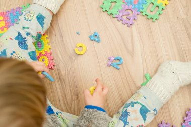 İki yaşındaki bir çocuk köpüklü bulmaca öğrenme numaralarıyla oynuyor. Öğrencileri saymak sayısal zemin oyunu oyuncakları öğrenme oyuncakları