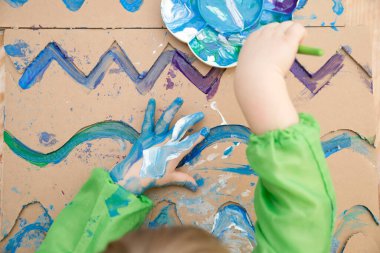 Sıfır kayıp. Arazi yapmak için oyulmuş karton kesilmiş ve yapıştırılmış. Çocuk onu deniz gibi boyuyor. Evdeki DIY oyunları. Okyanus konseptini koru.