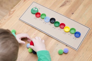 Plastik şişe kapağı solucanı. Doğru renk ponponları kırkayak tırtılına koyun. Beş dakikalık el işi. Çocuk yuvası aktivitesi. Erken eğitim, iyi motor becerileri. # Evde kal.