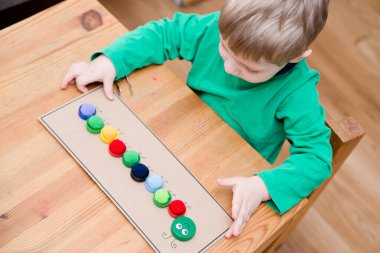Plastik şişe kapağı solucanı. Doğru renk ponponları kırkayak tırtılına koyun. Beş dakikalık el işi. Çocuk yuvası aktivitesi. Erken eğitim, iyi motor becerileri. # Evde kal.