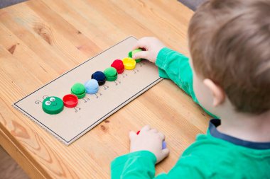 Plastik şişe kapağı solucanı. Doğru renk ponponları kırkayak tırtılına koyun. Beş dakikalık el işi. Çocuk yuvası aktivitesi. Erken eğitim, iyi motor becerileri. # Evde kal.