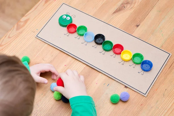 Plastik şişe kapağı solucanı. Doğru renk ponponları kırkayak tırtılına koyun. Beş dakikalık el işi. Çocuk yuvası aktivitesi. Erken eğitim, iyi motor becerileri. # Evde kal.