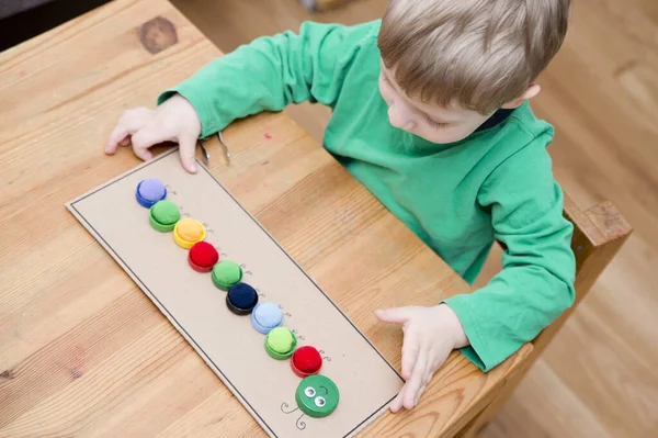 Plastik şişe kapağı solucanı. Doğru renk ponponları kırkayak tırtılına koyun. Beş dakikalık el işi. Çocuk yuvası aktivitesi. Erken eğitim, iyi motor becerileri. # Evde kal.