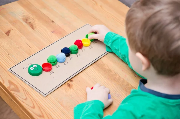 Plastik şişe kapağı solucanı. Doğru renk ponponları kırkayak tırtılına koyun. Beş dakikalık el işi. Çocuk yuvası aktivitesi. Erken eğitim, iyi motor becerileri. # Evde kal.