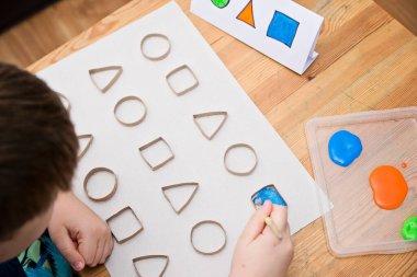 Çocuk geometrik şekilleri öğreniyor. Güzel motor beceriler. Anaokulu ya da özel görevler. Çocukların erken eğitimi. Montessori yöntembilimi.