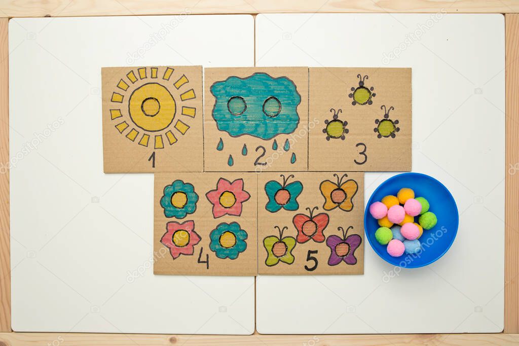 Hand made children home activity from cardboard and pom poms. Early education, Montessori methodology. Implement to develop fine motoric skills, logical thinking learn counting.