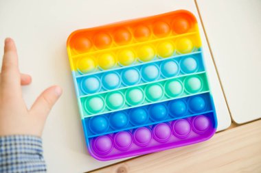 Çocuk duyusal oyuncak Pop-it ile oynuyor. Kaliteli motor becerileri için araç, saymaya başlamak için araç, birincil aritmetik işlemlerini öğrenmek. Parmak uyumu ve rahatlama için bir yatıştırıcı..