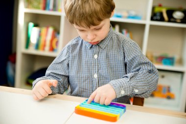 Çocuk duyusal oyuncak Pop-it ile oynuyor. Kaliteli motor becerileri için araç, saymaya başlamak için araç, birincil aritmetik işlemlerini öğrenmek. Parmak uyumu ve rahatlama için bir yatıştırıcı..